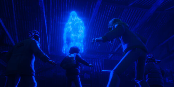 "Four people in winter clothes face a glowing blue ghostly figure hovering inside a dark, abandoned wooden building, illuminated by eerie blue light."